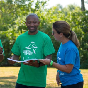 Girls on the Run coach is smiling at one of the program participant outdoors